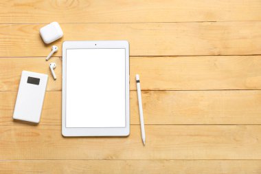 Ahşap arka planda modern tablet bilgisayar, kulaklık ve güç bankası