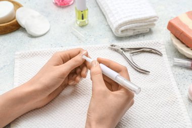 Kütikül yağı kalemleri, havlusu ve keskisi mavi grunge arka planda olan kadın elleri.