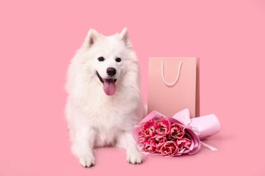 Güzel lale buketi ve pembe arka planda alışveriş çantası olan sevimli beyaz köpek.