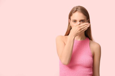 Young woman feeling terrible smell on pink background clipart