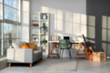 Çalışma yeri, raf ünitesi, kanepe, gitar ve dizüstü bilgisayarı olan şık bir ofis, bulanık görünüm