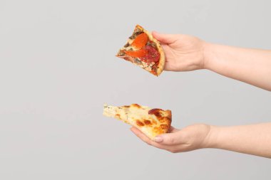 Beyaz arka planda lezzetli pizza dilimleri tutan kadın eller.