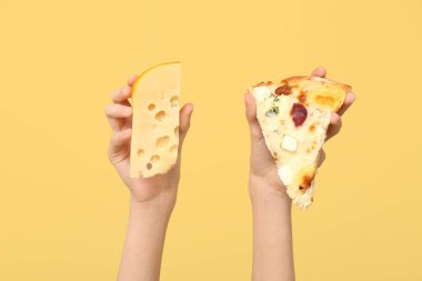 Sarı arka planda pizza dilimi ve peynir tutan kadın eller.