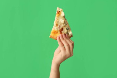 Yeşil arka planda lezzetli bir pizza dilimi tutan kadın.