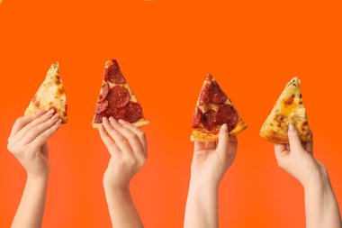 Birçok el turuncu arka planda lezzetli pizza dilimlerini tutuyor.