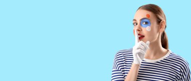 Boyalı vücutlu şık genç bir kadın mavi arka planda sessizlik jesti yapıyor ve metin için yeri var.