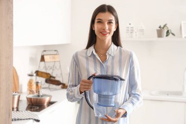 Mutfakta su filtresi olan genç bir kadın.