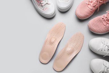 Bir çift ortopedik taban ve gri arka planda şık bayan ayakkabıları.