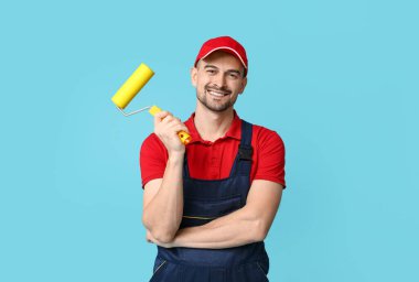 Mavi arka planda boya silindirli erkek ressamın portresi