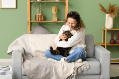 Evdeki kanepede oturan sevimli kedisi olan mutlu olgun bir kadın.