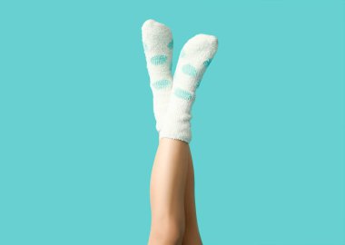 Mavi arka planda sıcak beyaz noktalı çoraplı genç kadın bacakları.