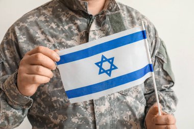 Hafif arka planda İsrail bayrağı taşıyan erkek Yahudi asker, yakın plan.