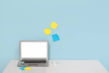 Masadaki modern dizüstü bilgisayar ve duvardaki yapışkan notlar