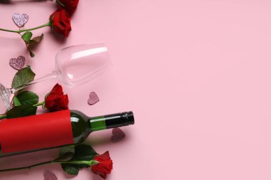 Gözlüklü bir şişe şarap ve pembe arka planda kırmızı güller. Sevgililer Günü kutlaması