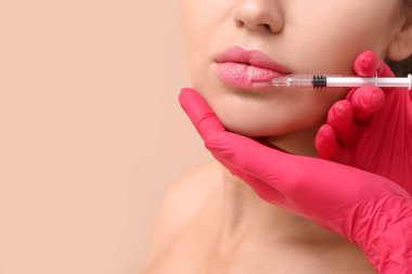 Renk arkaplanına karşı dudak enjeksiyonu alan genç kadın, yakın plan