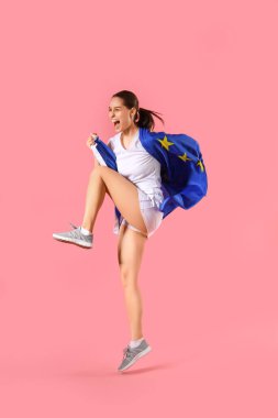 Pembe arka planda Avrupa Birliği bayrağı taşıyan sportif genç kadın