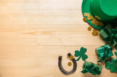 Leprikon şapkalı hediye kutuları, at nalı ve dekoru açık ahşap arka planda Aziz Patrick Günü kutlamaları için.