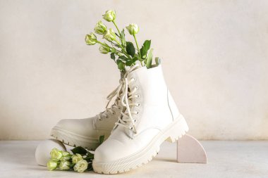 Beyaz arka planda güller olan beyaz çizmeler