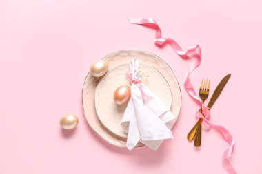 Paskalya yumurtaları ve pembe arka planda çigila çiçekleri olan güzel bir masa.