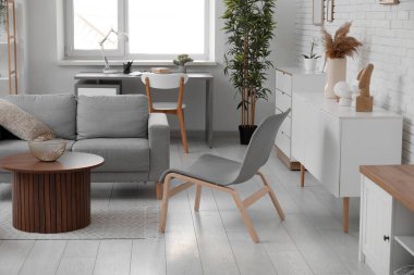 Gri koltuklu ve sandalyeli bir oturma odası.