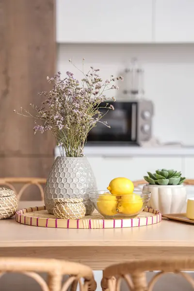 Wooden table with dried lavender, lemons and wicker tray in modern kitchen