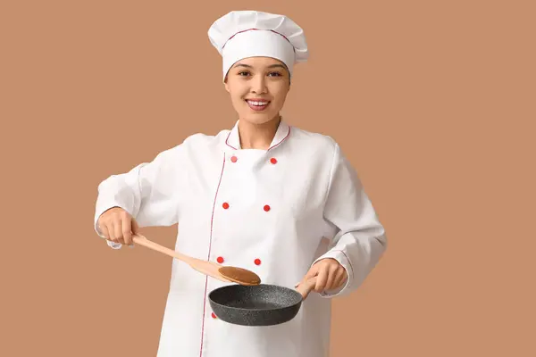 茶色の背景にフライパンに美味しいパンケーキを入れる若いアジアの女性シェフ — ストック写真