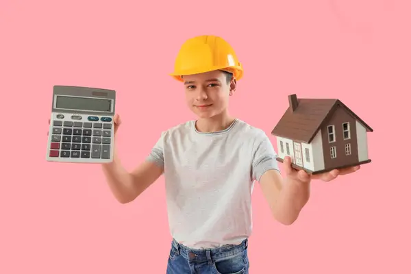 粉红背景的带计算器和房屋模型的小建筑师 — 图库照片