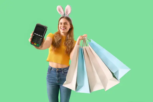 Junge Frau Hasenohren Mit Zahlungsterminal Und Einkaufstaschen Auf Grünem Hintergrund — Stockfoto