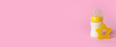 Bebek için bir şişe süt ve pembe arkaplanda da metin için boşluk.