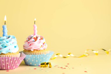 Sarı arka planda yanan mumları olan enfes doğum günü kekleri.