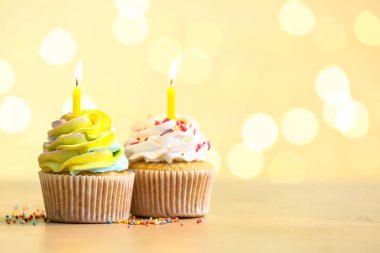 Bulanık ışıklara karşı yanan mumları olan lezzetli doğum günü kekleri.