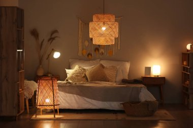 Yatak odasının içinde, yatakta battaniyeler ve akşam lambaları var.