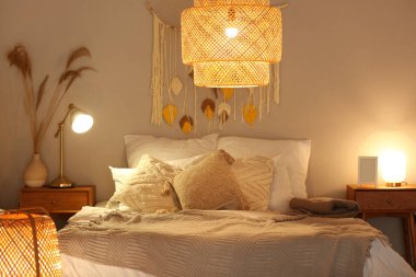 Yatak odasının içinde, yatakta battaniyeler ve akşam lambaları var.