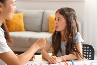 Logopedik sondası olan Asyalı kadın konuşma terapisti ve masadaki küçük kız.