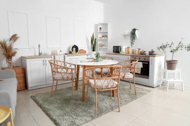 Yeşil bitkilerle, tezgahlarla ve yemek masalarıyla aydınlık mutfağın içinde.