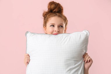 Pembe arka planda beyaz yumuşak yastıklı güzel bir kadın.