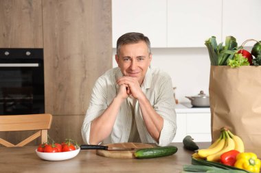 Mutfaktaki masada sağlıklı yemekleri olan olgun bir adam.