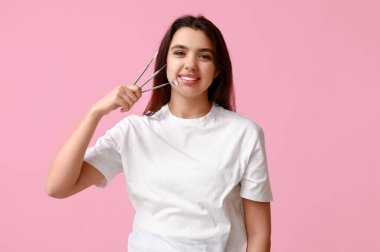 Pembe arka planda aletleri olan kadın dişçi. Dünya Diş Hekimi Günü