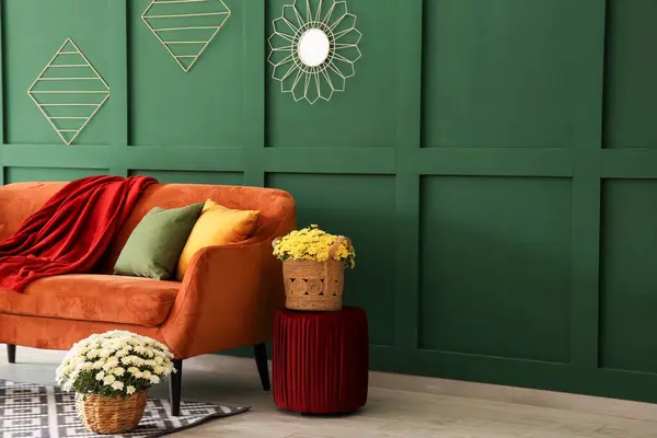 Interior of modern living room with orange sofa and chrysanthemum flowers