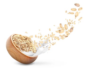 Süt damlaları ve beyaz arka planda yuvarlanan yulaflarla dolu bir kase.