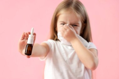 Pembe arka planda doku ve burun damlaları olan hasta küçük kız, yakın plan.