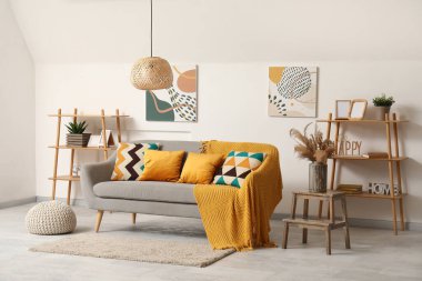 Rahat kanepesi, resimleri, yastıkları ve rafları olan güzel bir oturma odası.