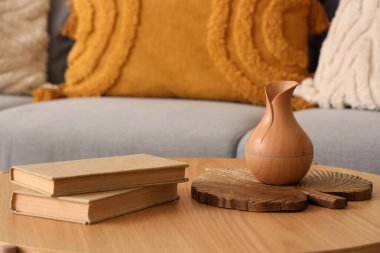 Sehpanın üzerinde kitaplar olan vazo, şık gri kanepenin yanında.