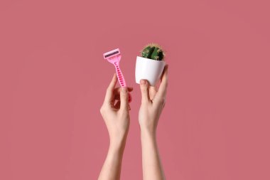 Pembe arka planda jilet ve kaktüs olan kadın elleri.