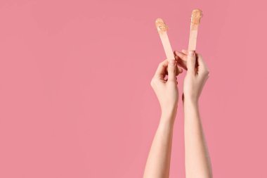 Pembe arka planda şekerli spatula tutan kadın elleri.