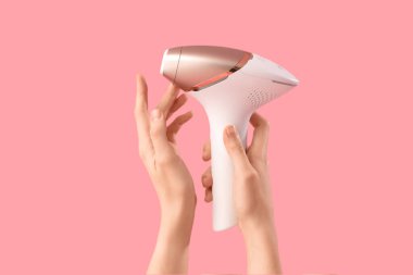 Pembe arka planda modern fotoğraf makinesi olan kadın eller, yakın plan.