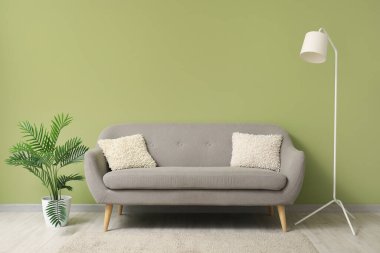 Yeşil duvarın yanındaki modern oturma odasının şık iç mekanı.