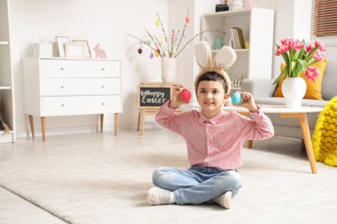 Tavşan kulaklı ve paskalya yumurtalı şirin bir çocuk oturma odasında yerde oturuyor.