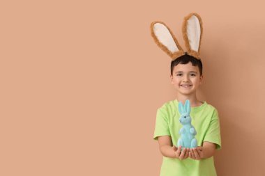 Tavşan kulaklı ve bej arka planda oyuncak tavşanı olan şirin bir çocuk. Paskalya kutlaması