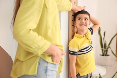 Genç anne, evdeki ahşap stadyumun yanında küçük oğlunun boyunu ölçüyor.